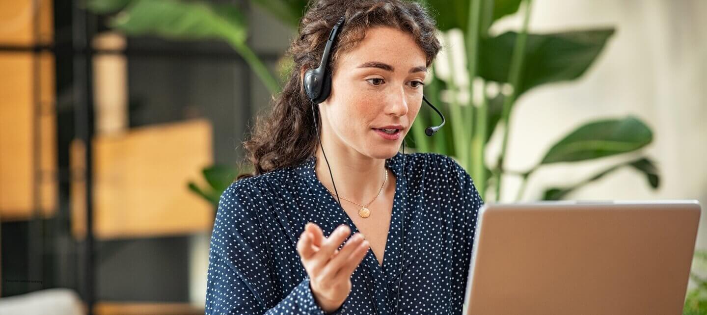 Female contractor on a video call using a headset and laptop.