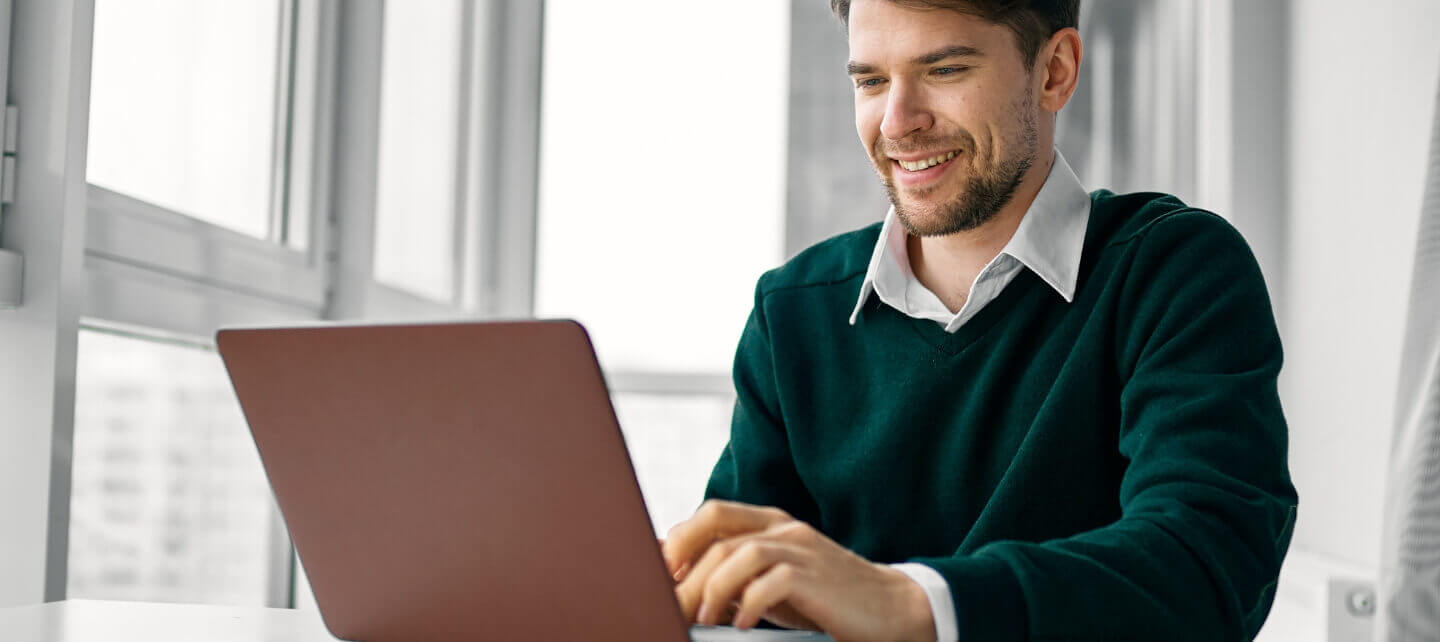 Contractor working at a desk on a laptop in a modern office.
