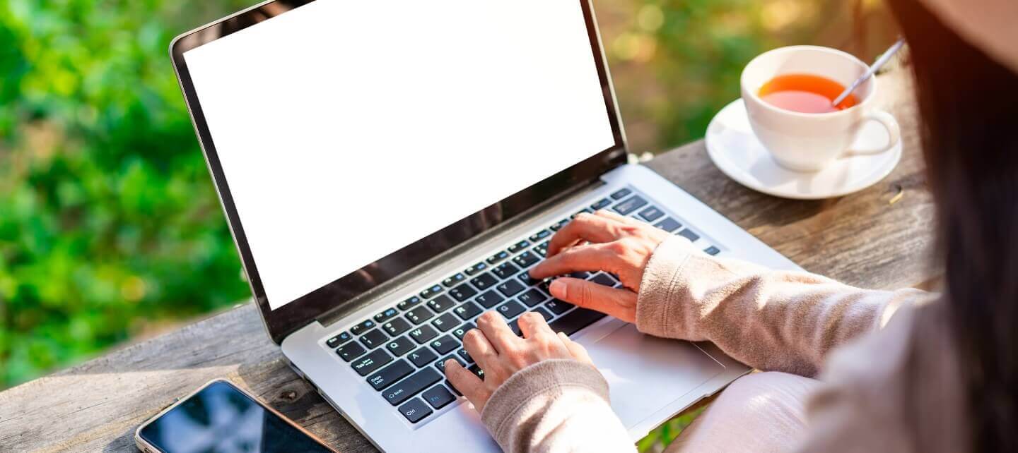 Young professional working remotely from home, focusing on his phone and laptop.