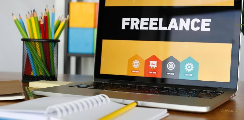 Close-up of a laptop screen with the word 'freelancing' in a bright office environment, suggesting a freelance work setup.