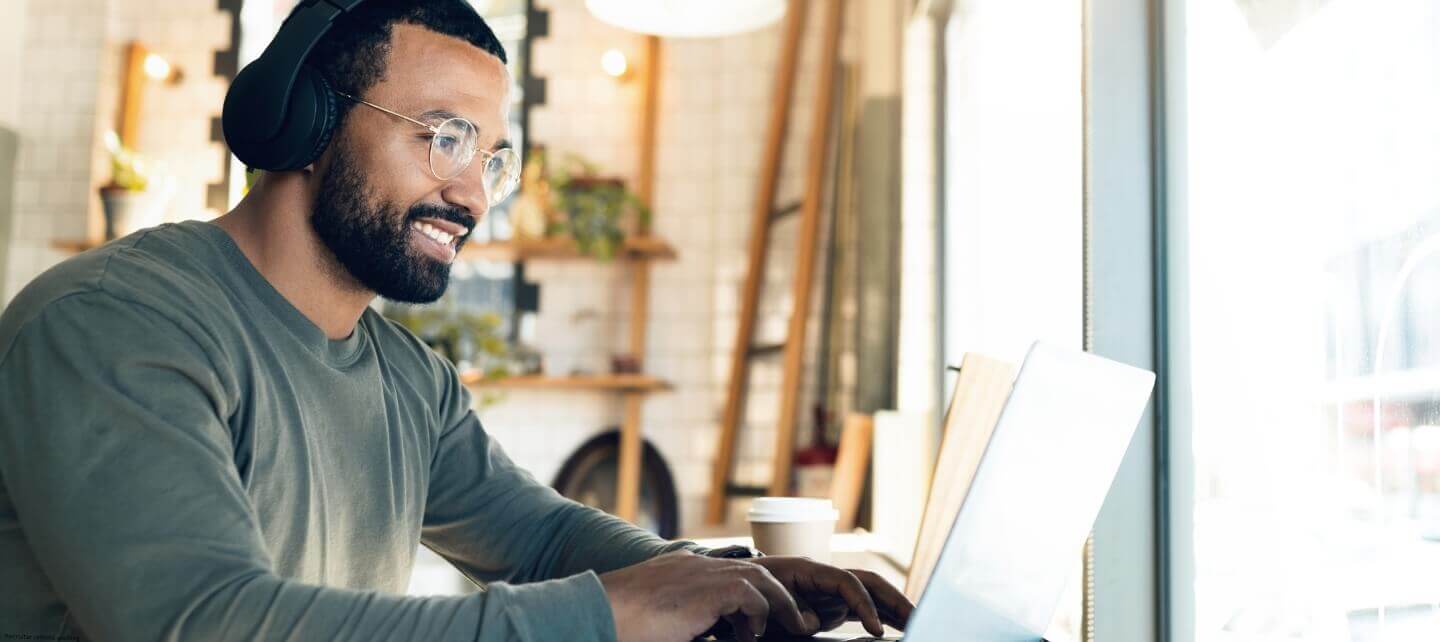 Professional working remotely on a laptop while wearing headphones.