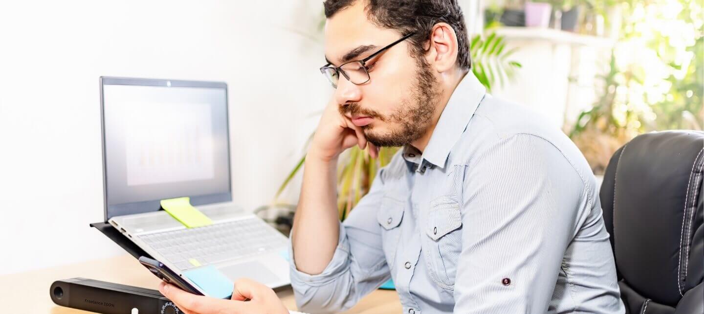 Person working on a laptop outdoors with a cup of tea, representing a remote working setup.