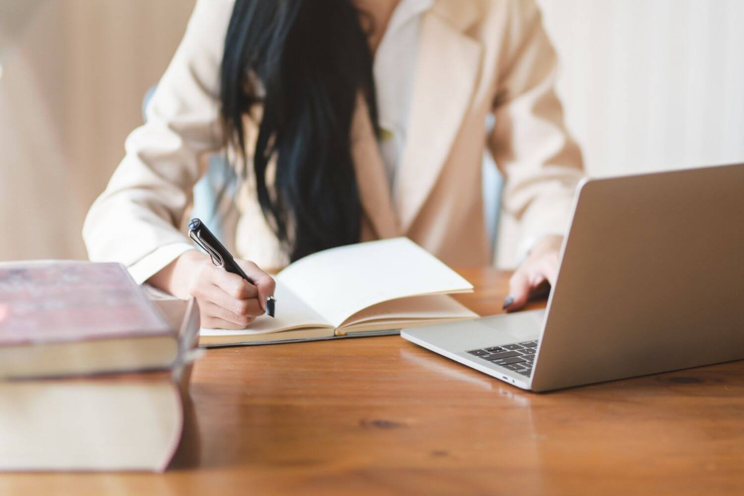 A woman sits at a laptop making notes