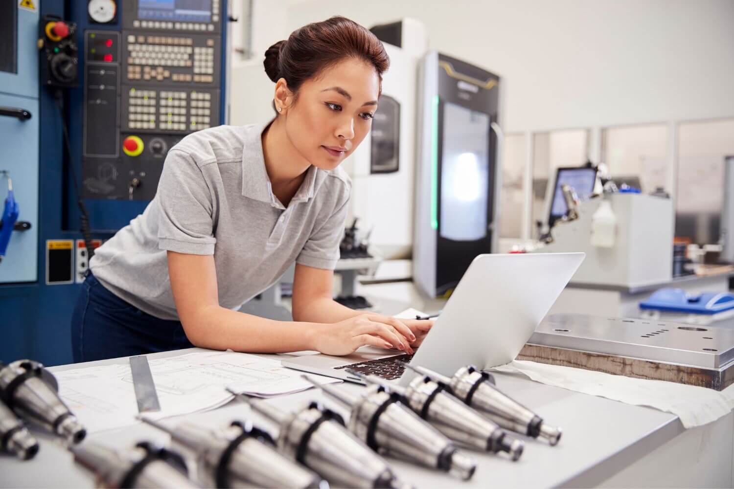 Asian woman at a laptop surrounded by mechanical elements