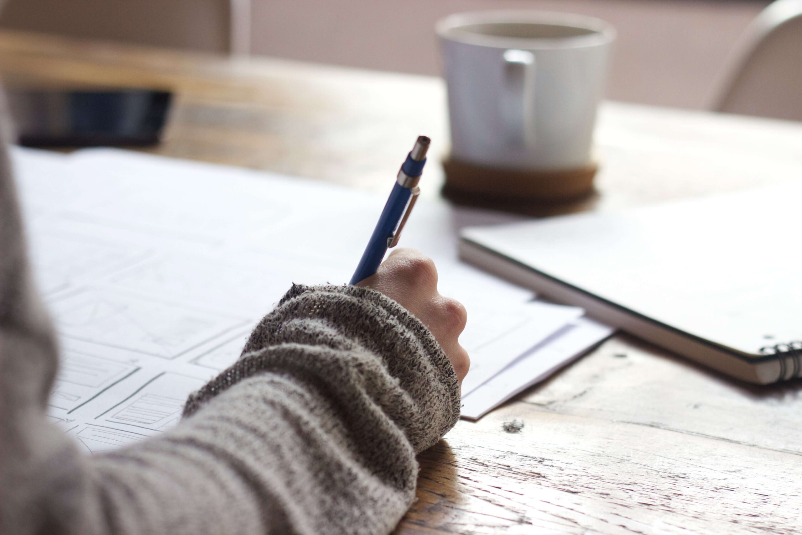 Person writing a response to HMRC's IR35 compliance check letters, with documents on the table.