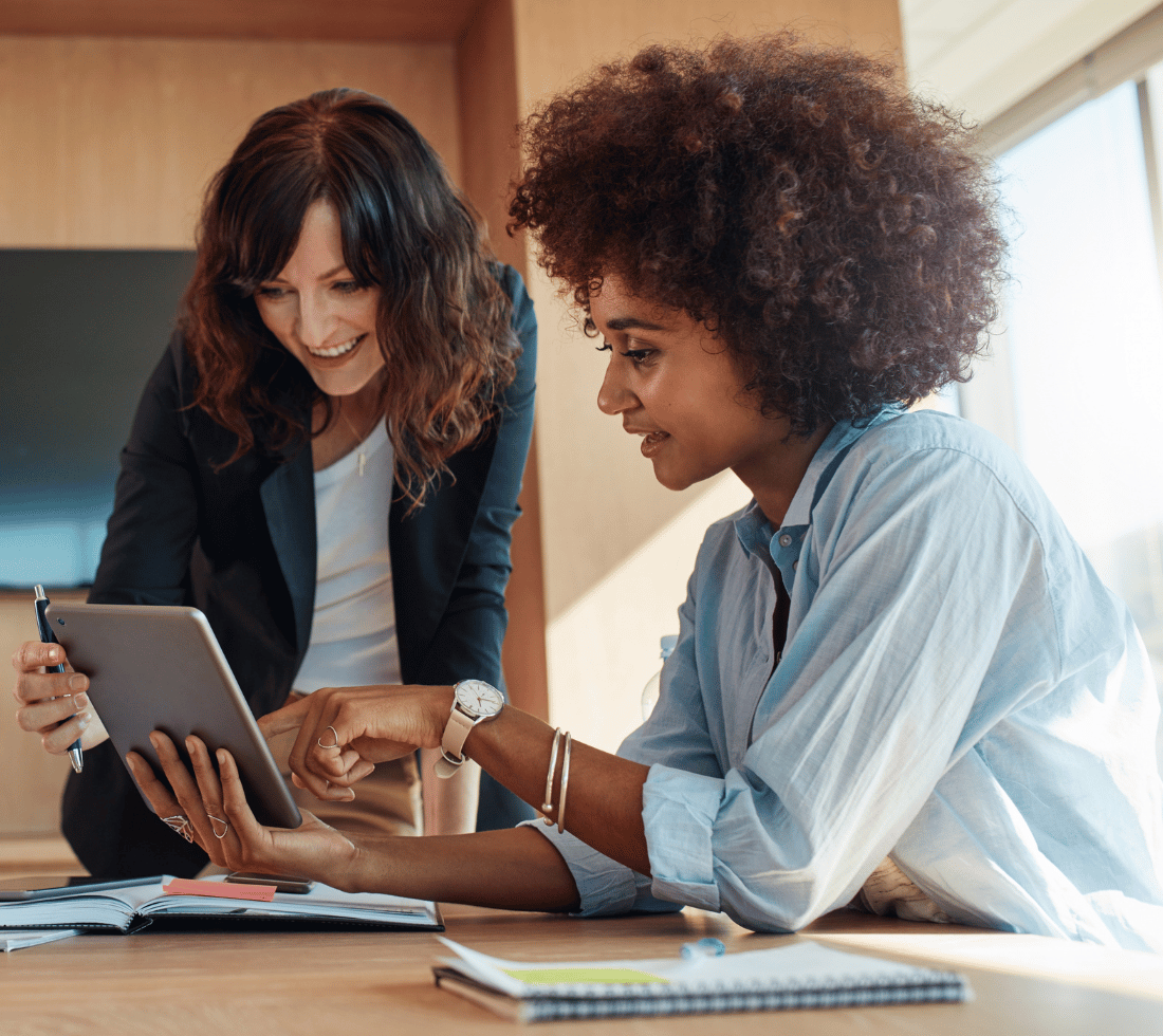 Two female workers in the office working on a tablet together