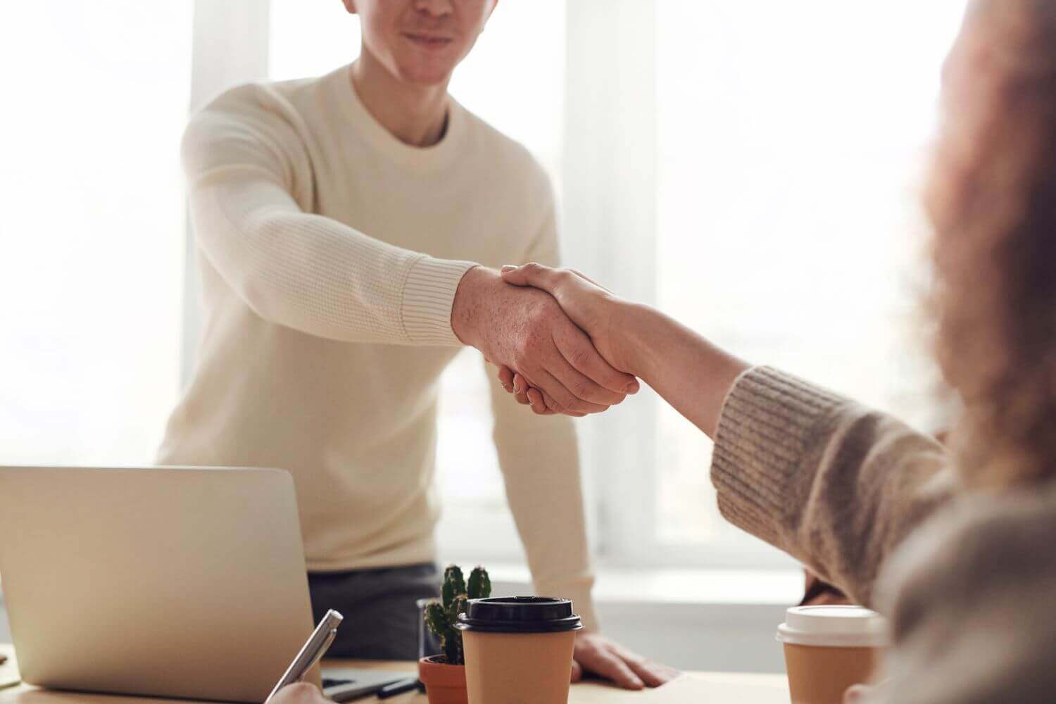 Image: business shaking hands. Article discusses the recent employer's national insurance contribution changes, day-1 worker rights and the possible impact of hiring strategies