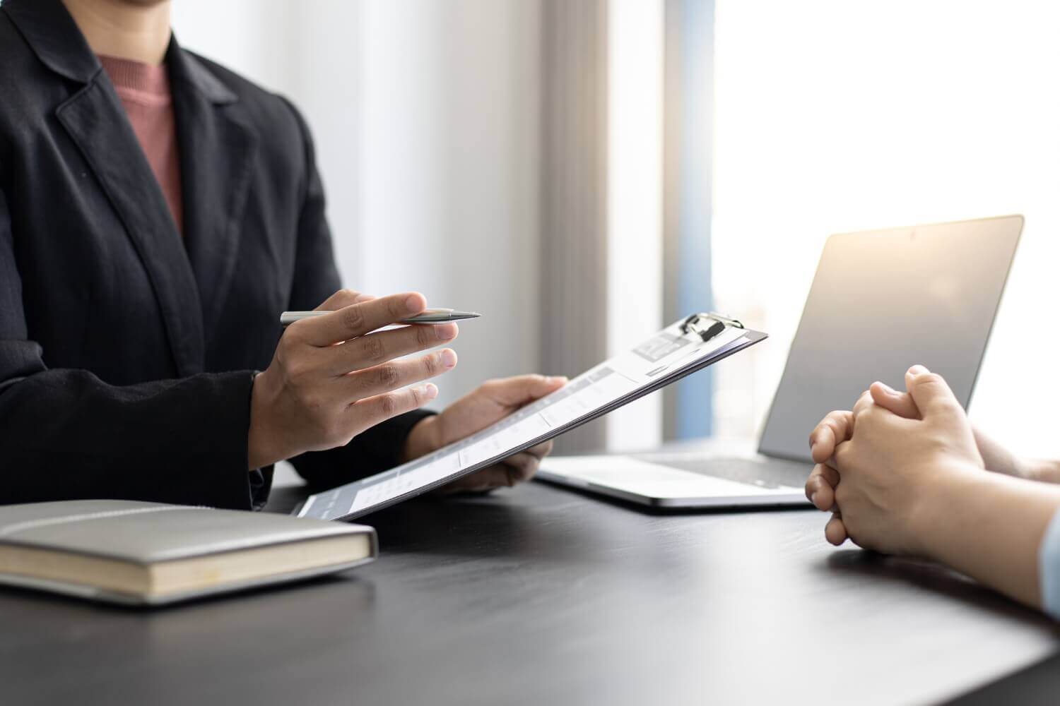 Businessperson discussing contractor status and IR35 determination during a compliance meeting, with paperwork and a laptop on the table