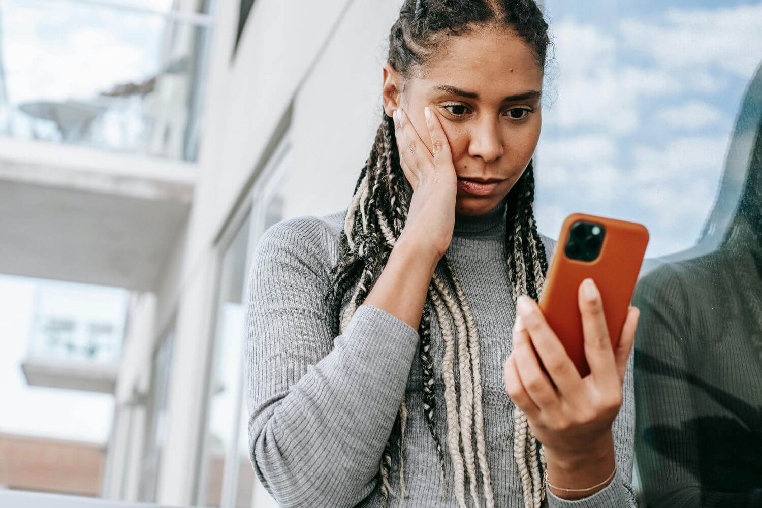 Image of concerned person looking at phone, representing article with contacts and steps for how to report cyber crime