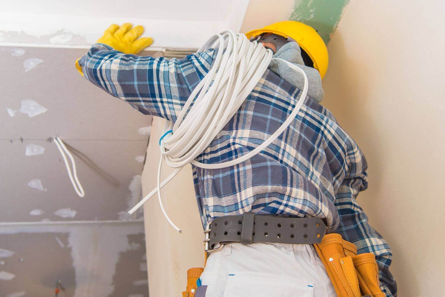 Image of electrician installing ceiling wiring, representing a guide to tradesman business insurance and what it can cover