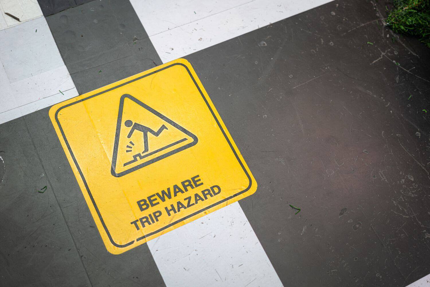 Image of trip hazard sign, representing article explaining employers' liability insurance requirements and who is exempt