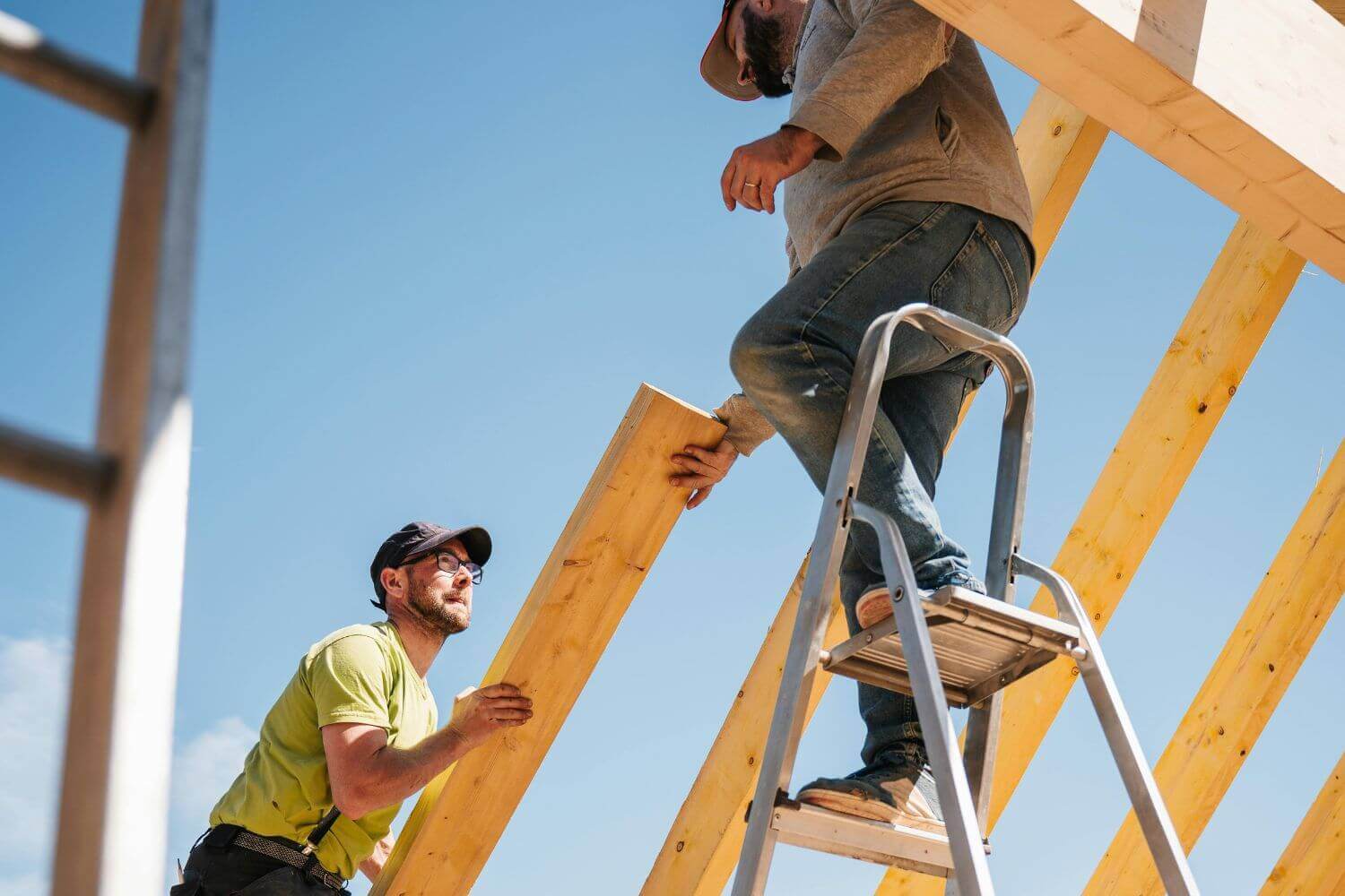 Image of two builders carrying construction materials, representing article on do subcontrctors need their own insurance