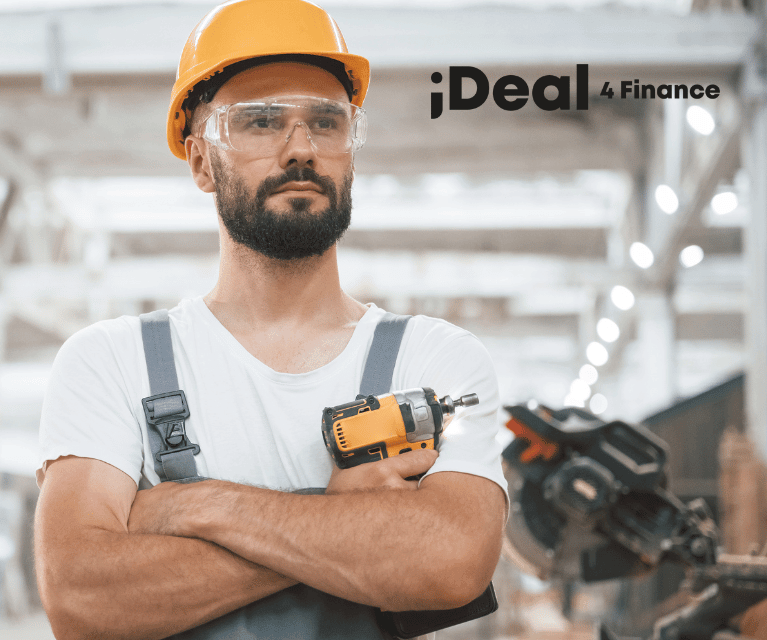 Tradesman in a warehouse wearing a hardhat and holding a wireless drill