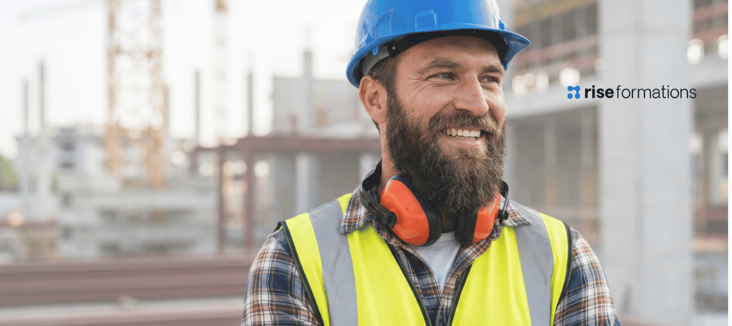 Construction worker on a construction site wearing a hardhat, ear defenders and a high-visibility vest