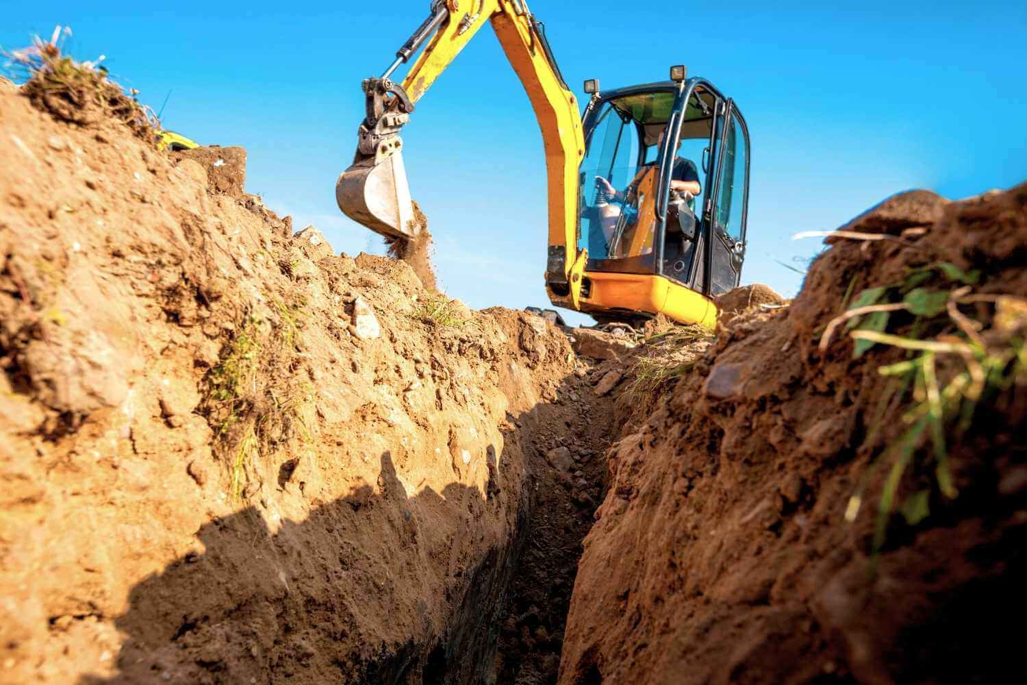 Photo of dug out earth with construction worker on mini excavator, representing article on plant and machinery insurance